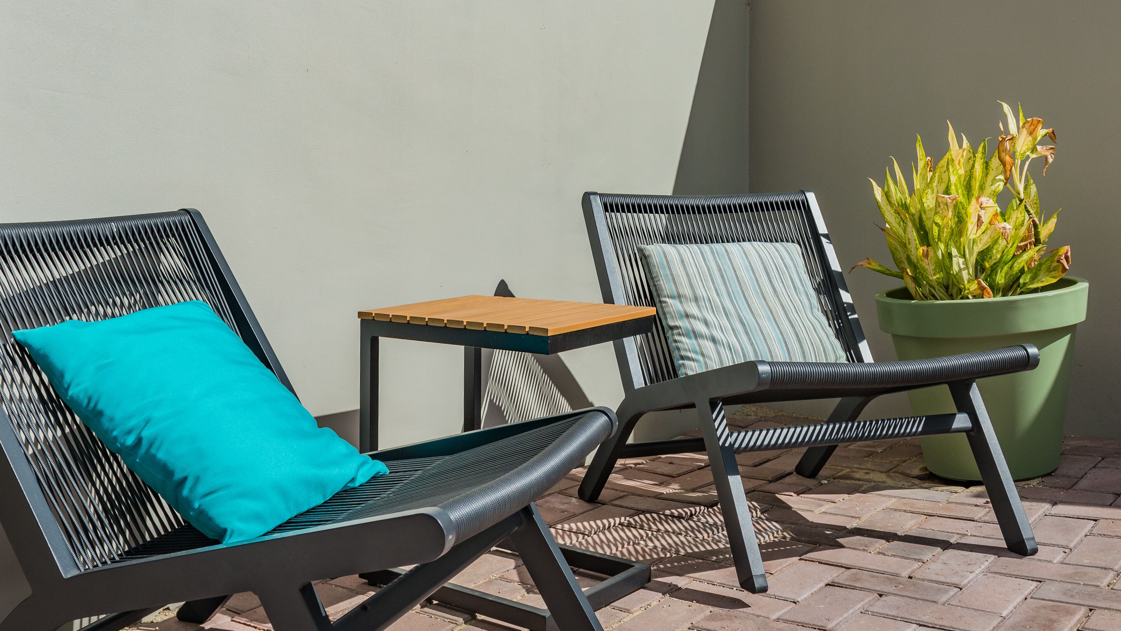 Deux chaises d’extérieur avec coussins, une petite table et une plante en pot.