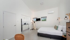Een moderne, goed verlichte slaapkamer met een bed, nachtkastje en een kleine potplant.