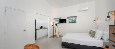 Un dormitorio moderno y luminoso con una cama, mesita de noche y una pequeña planta en maceta.