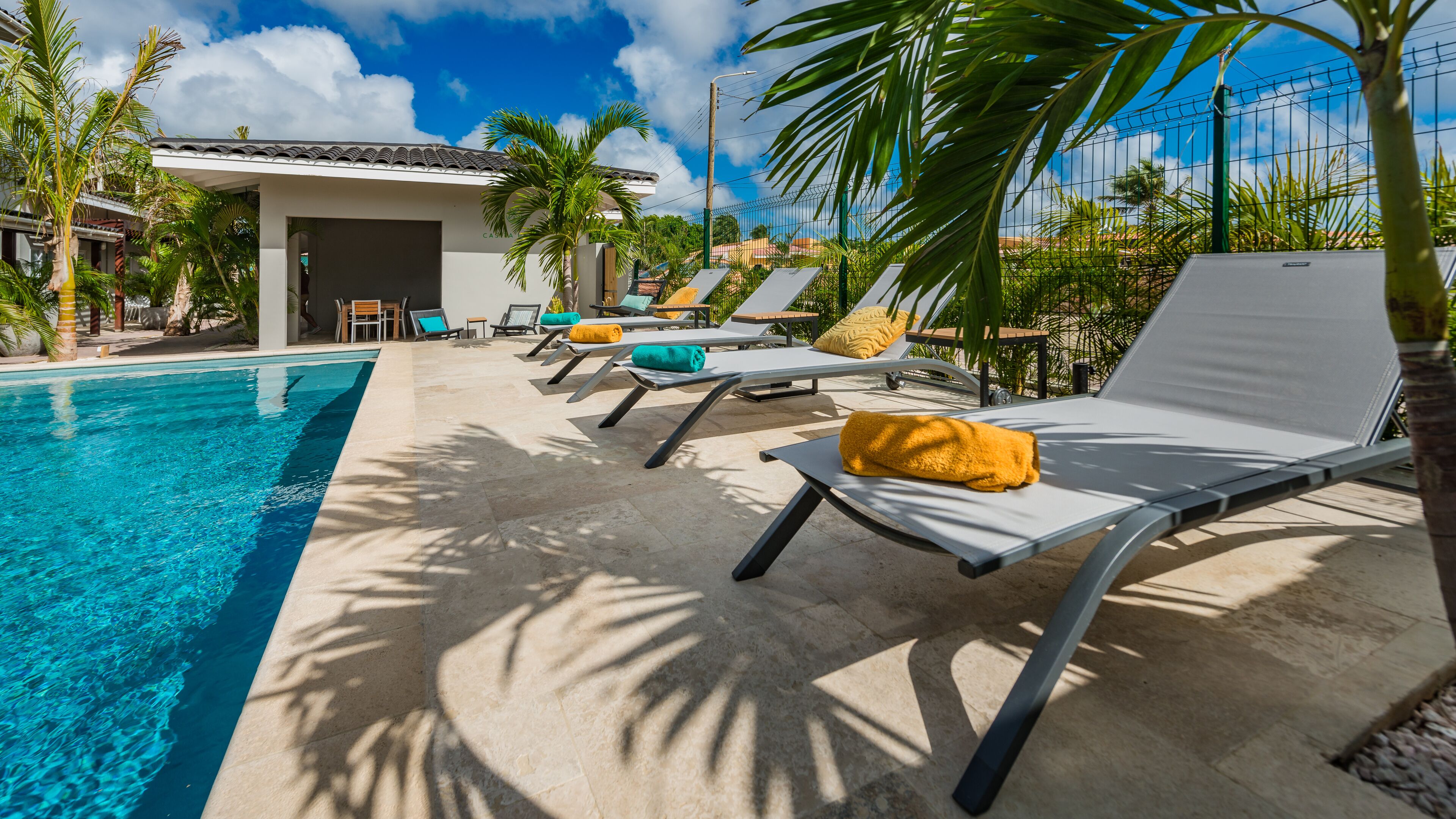 Area piscina con lettini e un edificio sullo sfondo.