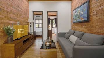 Un salón moderno con un sofá gris, una mesa de centro de madera y un televisor sobre un mueble de madera.