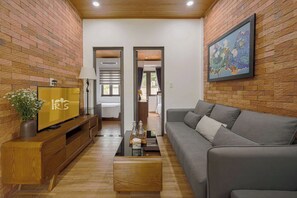 Un salón moderno con un sofá gris, una mesa de centro de madera y un televisor sobre un mueble de madera.