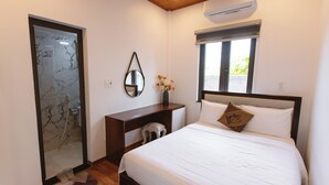 Un dormitorio con cama, escritorio, espejo y ventana.