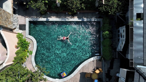 Vista aérea de una piscina con agua cristalina, rodeada de vegetación y un muro de piedra.