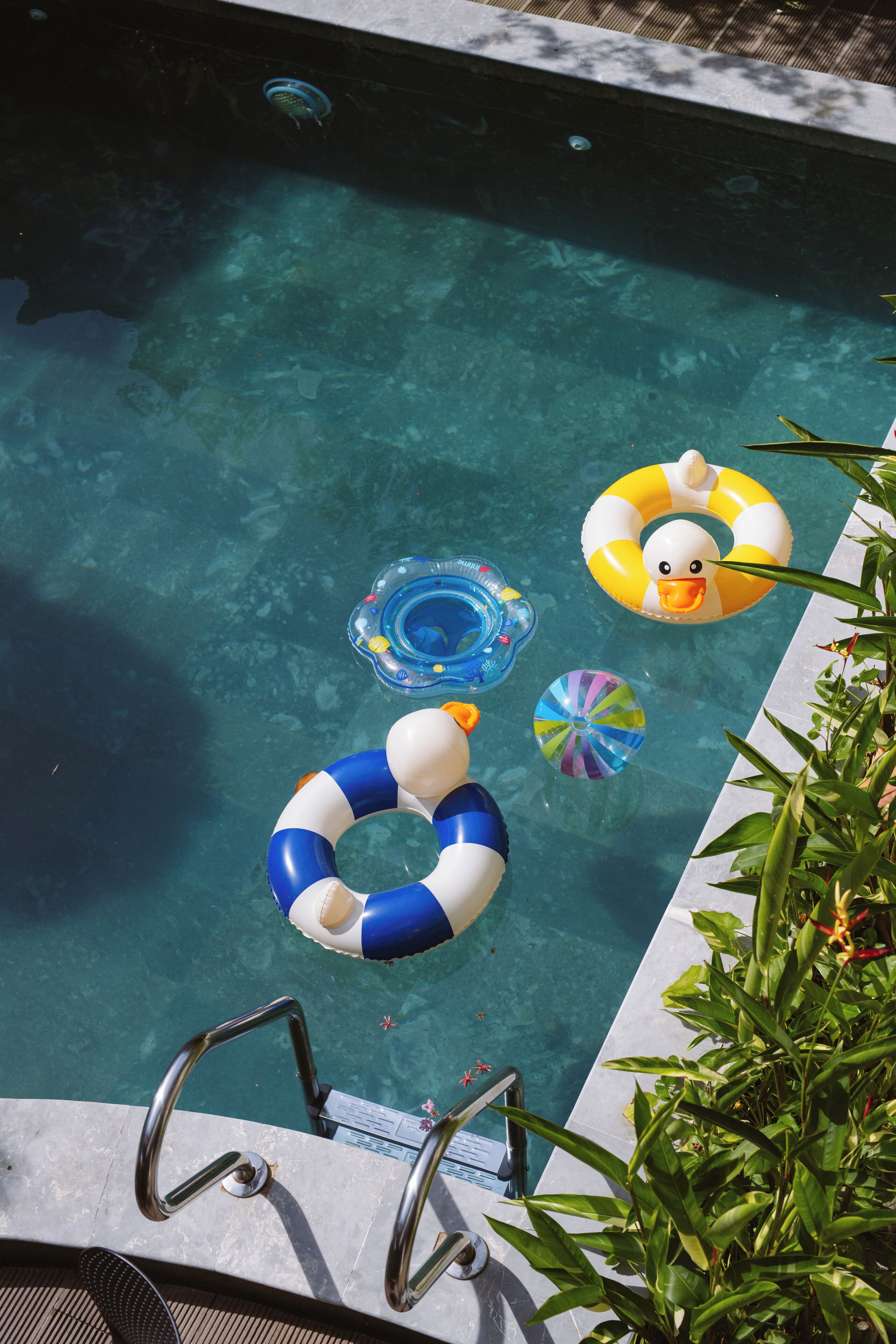 Una piscina cristalina con un trampolín y diversos flotadores hinchables.