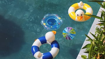 Una piscina cristalina con un trampolín y diversos flotadores hinchables.