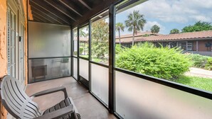 A covered balcony with a view of a courtyard, featuring a chair and a table. - Naples Resort Retreat w/ Pool Access! (Naples)