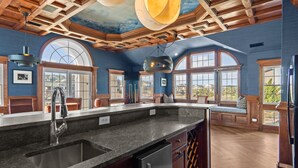 A kitchen with a granite countertop, stainless steel sink, and wooden cabinets. - 2876 - The Blue Martini - Oceanfront Luxury Retreat w/ Pool & Sauna (Duck)