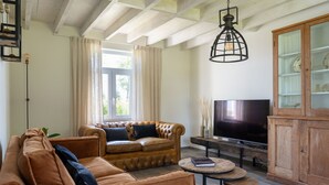 Una sala de estar con un sofá de cuero, un televisor y un mueble de madera.