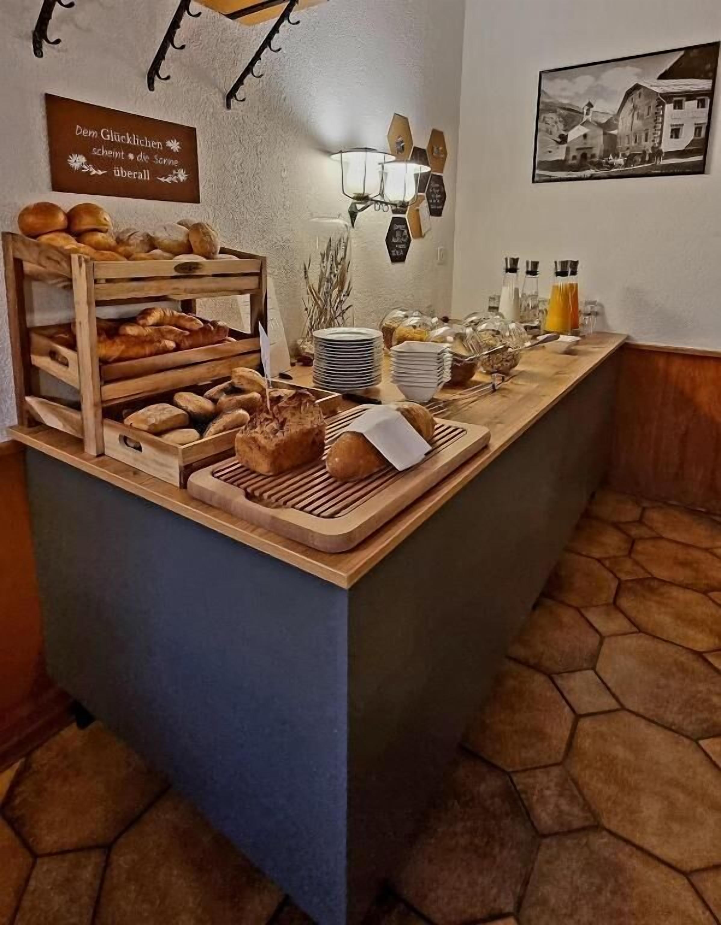 A breakfast bar with bread, pastries, and condiments.