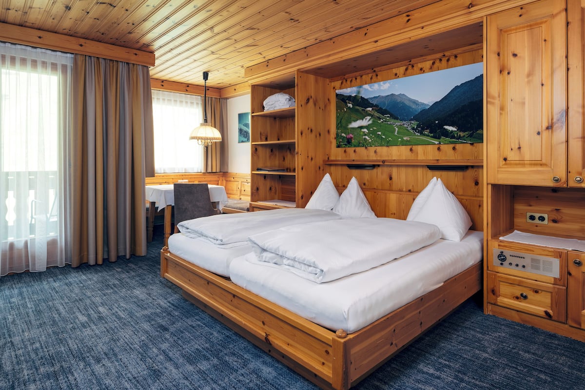 Ein Schlafzimmer aus Holz mit einem großen Bett, einem Schreibtisch und einem an der Wand befestigten Fernseher.
