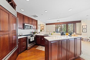 A kitchen with wooden cabinets, a stainless steel stove, and a large island with a sink.
