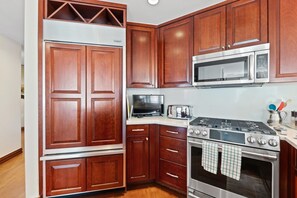 A kitchen with wooden cabinets, a microwave, a toaster, and a stove.