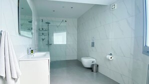 A modern bathroom with a glass shower enclosure, a white sink, and a toilet. - Phaedrus Living Plateia Suite Grigio (Nicosia)