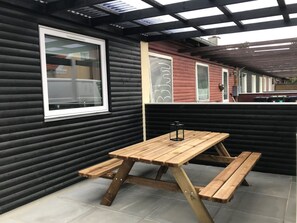 Enjoy a meal or relax on the patio with a wooden table and benches under a covered pergola.