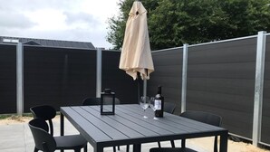 An outdoor patio with a table and chairs, a bottle of wine, and a lantern.