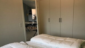 A room with a bed, a wardrobe, and a kitchenette in the background.