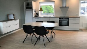 A modern kitchen with white cabinetry, a dining table with black chairs, and a window providing natural light.