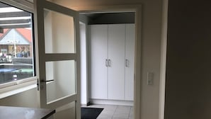 A room with a sliding door leading to a closet with two doors and a window with a view of a street.