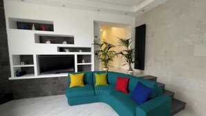 Una sala de estar moderna con un sofá modular color turquesa, paredes blancas y estanterías empotradas.