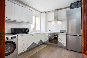 Une cuisine compacte équipée d’un lave-linge, d’un four à micro-ondes, d’un four et d’un réfrigérateur.