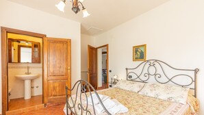 Un dormitorio con cama, armario de madera, baño con lavamanos y espejo.