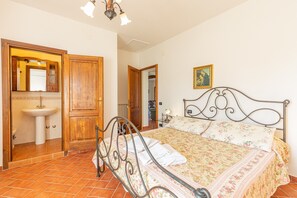 Un dormitorio con cama, armario de madera, baño con lavamanos y espejo.
