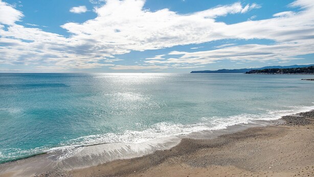 A beach with clear water, a sandy shore, and a distant coastline. - Rosa Corallo Deluxe – Historic Center Apartment with Wi-Fi and Air Conditioning (Varazze)