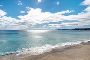 Una playa con agua cristalina, una orilla arenosa y una costa distante.