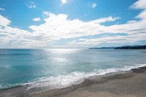 A beach with clear water, a sandy shore, and a distant landmass.