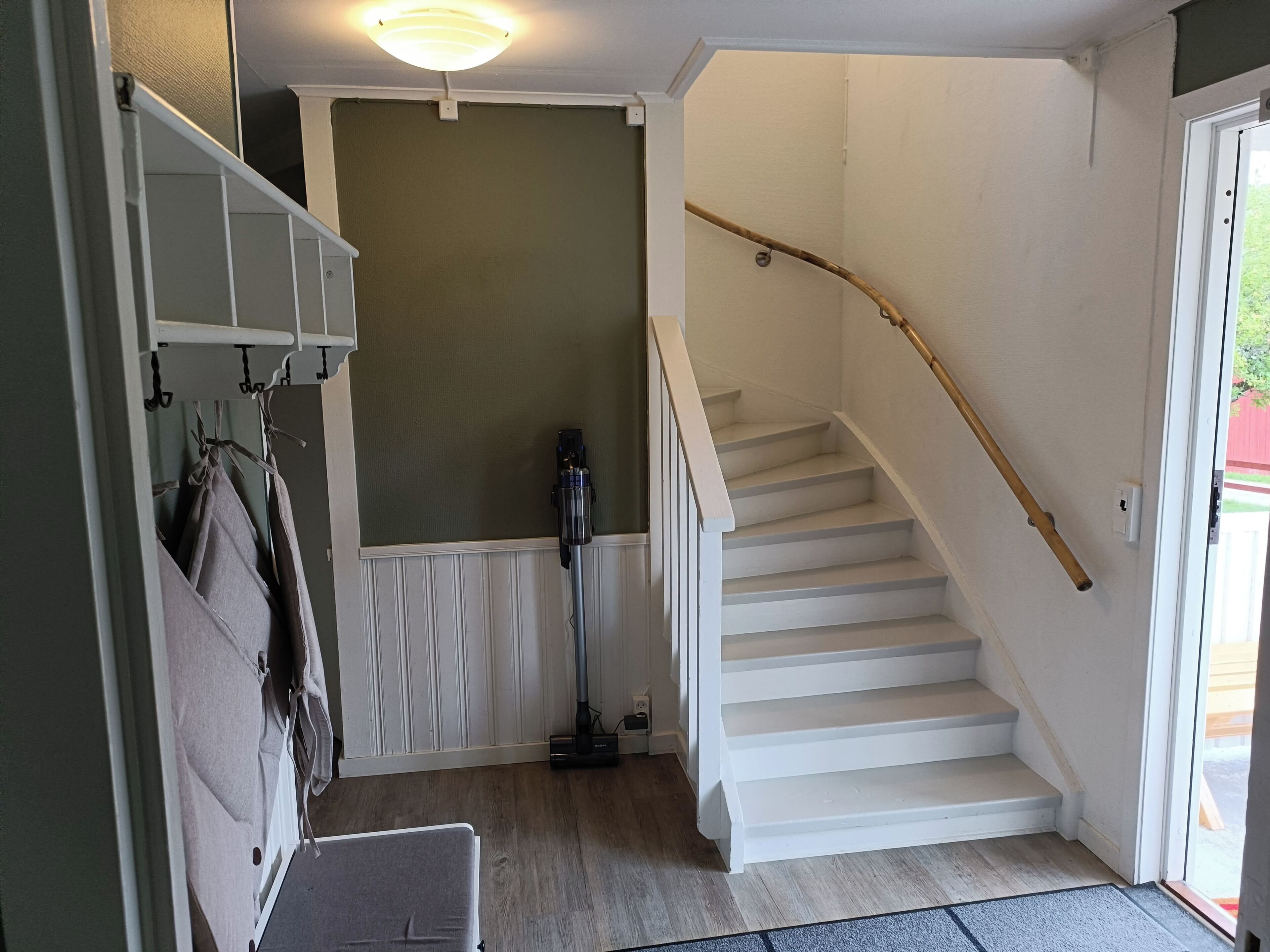 Una escalera con barandilla de madera que lleva a una plataforma con lámpara de techo.