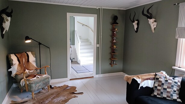 A room with a sofa, a fur rug, and mounted animal skulls on the wall. - 2 bedroom villa in ã-stergã¶tlands lã¤n (Östergötlands län)