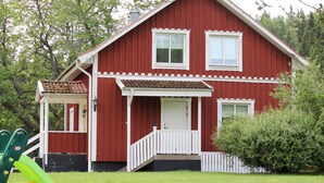 A red house with a porch, a green slide, and a white fence. - 2 bedroom villa in ã-stergã¶tlands lã¤n (Östergötlands län)