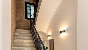 Un escalier avec des marches en marbre et une rampe en fer forgé, menant à un ascenseur.