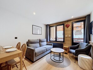 A modern living room with a sofa, chairs, a dining table, and a small coffee table.