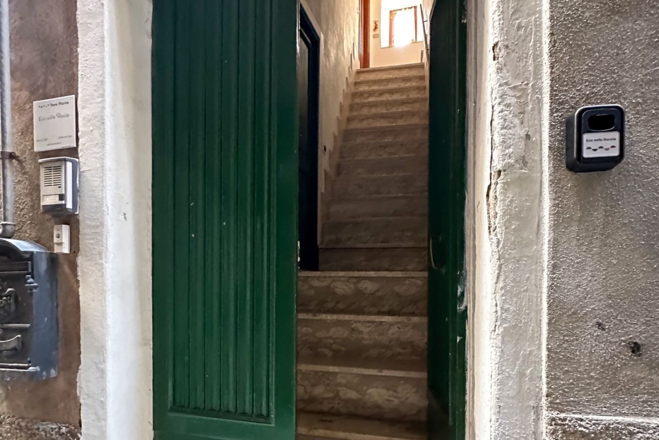 A staircase leading to an upper floor, a green door, and a wall-mounted electrical outlet.