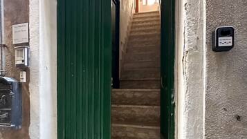 A staircase leading to an upper floor, a green door, and a wall-mounted electrical outlet.