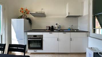 A modern kitchen with white cabinets, a stainless steel range hood, a built-in oven, and a sink.