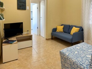 A living room with a TV, sofa, and ottoman.