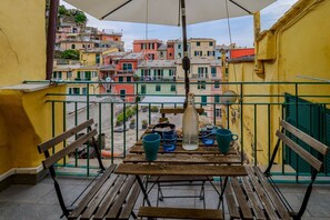 A balcony with a table, chairs, and a hanging light fixture.