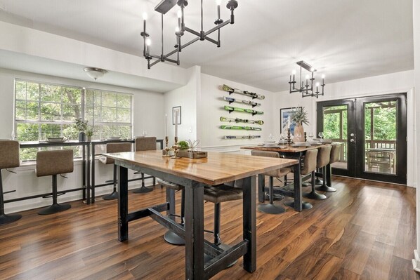 A modern dining area with a wooden table, black chairs, and pendant lighting.
