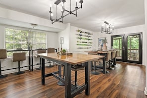 A modern dining area with a wooden table, black chairs, and pendant lighting. - Crestwood Lodge: Hot Tub & Pets! (Birmingham)