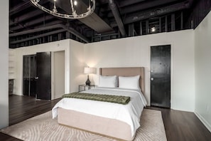 Un dormitorio moderno con una cama grande, una mesita de noche, una lámpara y un candelabro.