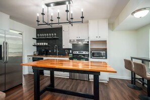 Eine moderne Küche mit einer Holzeinsel, Edelstahlgeräten und einer schwarzen Spritzschutzwand.
