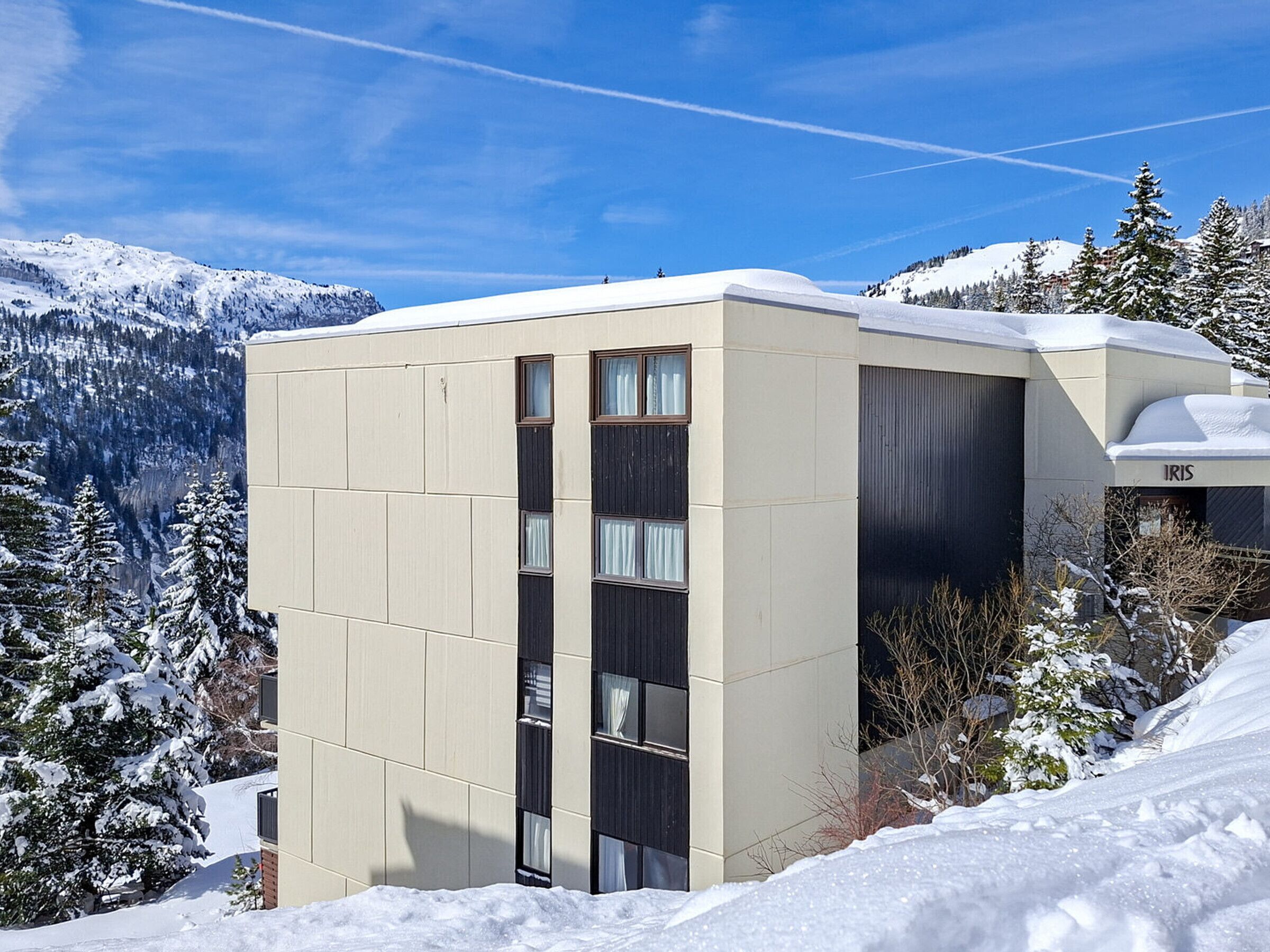 Un edificio moderno con techo plano, ventanas amplias y un letrero que dice 'IRIS'.