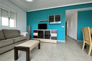 Ein Wohnzimmer mit einer Couch, einem Couchtisch, einem Fernseher und einem Schrank.
