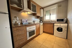 Eine kompakte Küche mit Kühlschrank, Backofen, Mikrowelle und Waschmaschine.