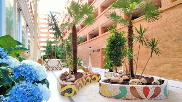 A hotel corridor with tiled flooring, potted plants, and a sign indicating the name of the hotel. - ACV - Torremar-2nd line 7th floor Frontal (Oropesa)