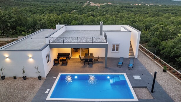 Una casa moderna con piscina, area relax esterna e vista sulla foresta circostante.