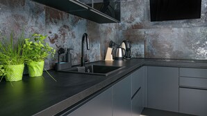 Una cucina moderna con piano di lavoro nero, elettrodomestici in acciaio inossidabile e un backsplash rustico con texture.